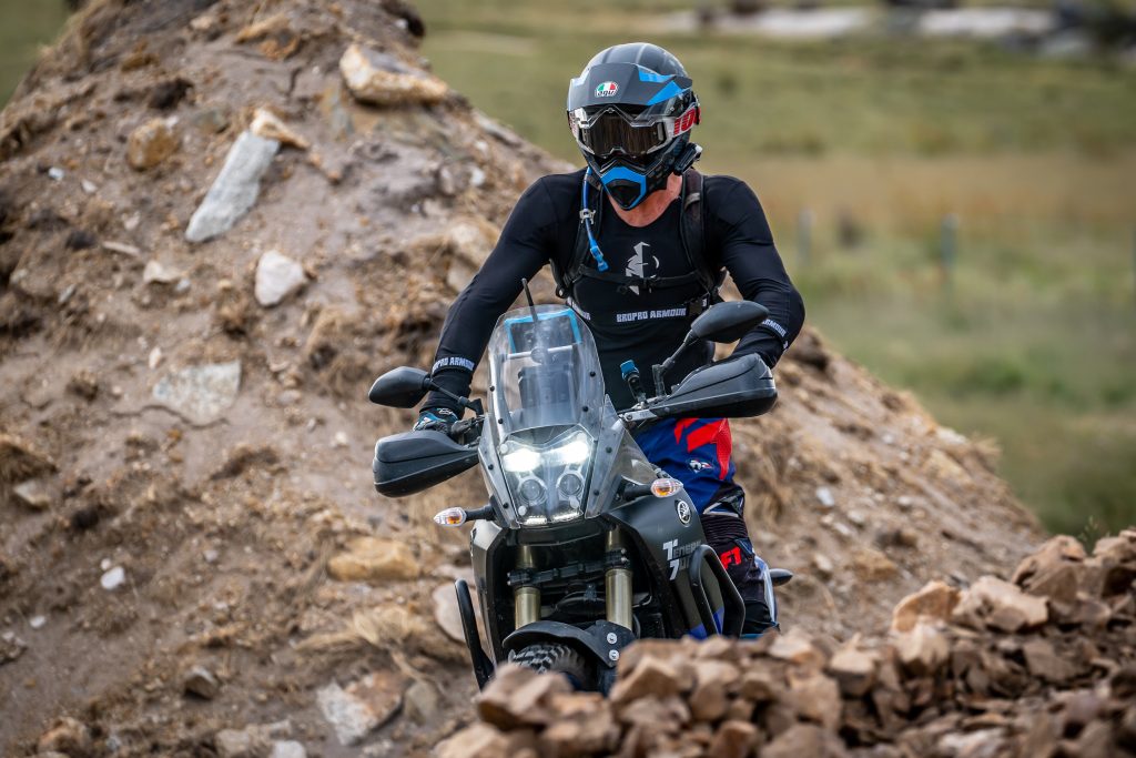 Motorcyclist riding on rough terrain with a focused expression