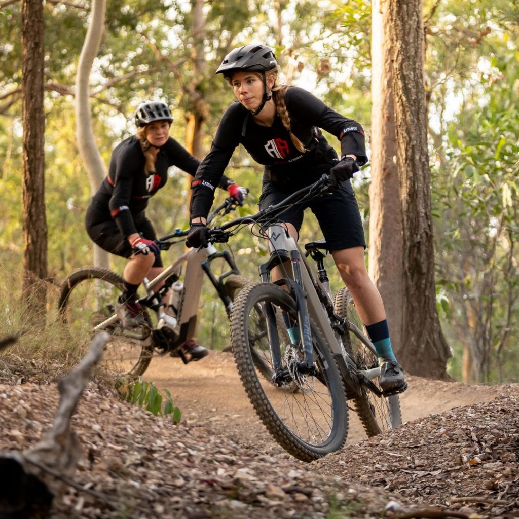 two mountain bikers navigating a trail through a forested area