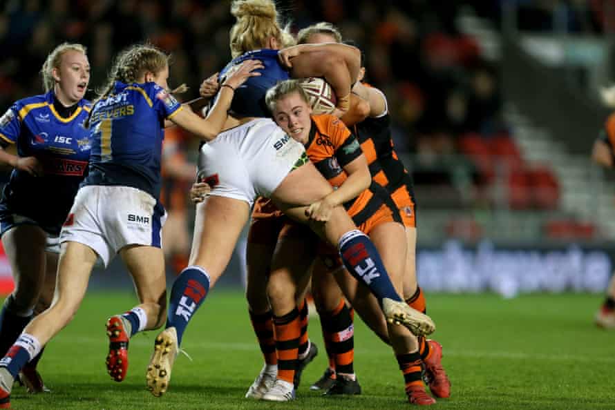 female rugby players in a tense tackle during a night game