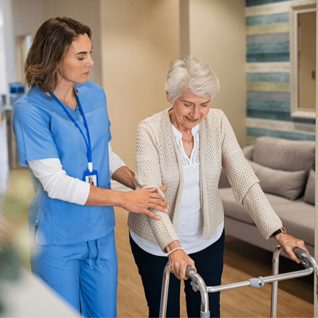 elderly woman using a walker with assistance from a healthcare worker