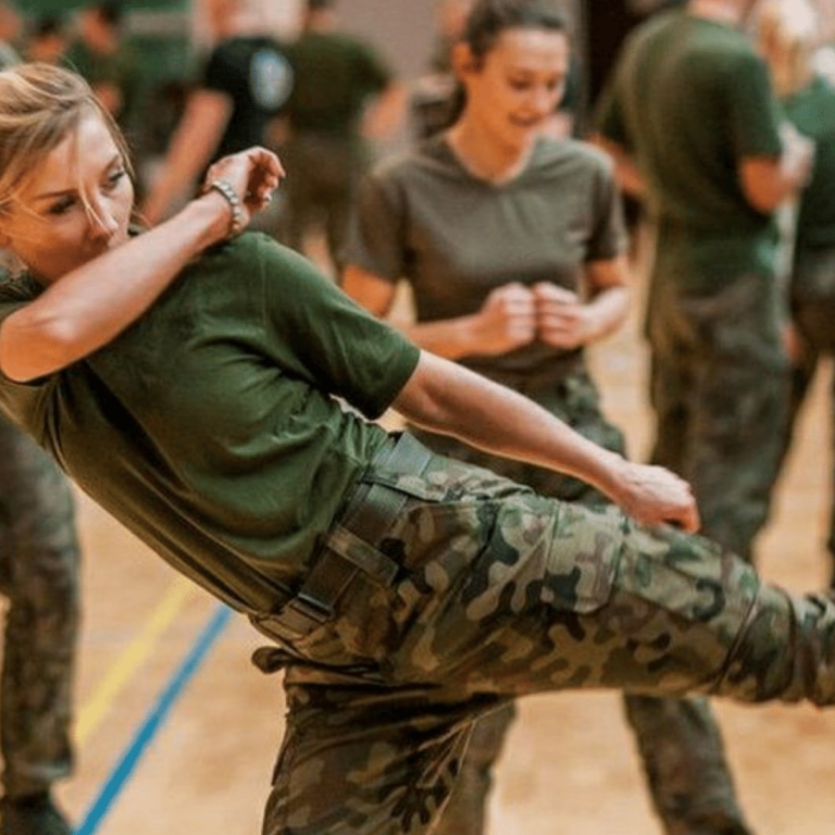 a woman in military attire practicing a high kick in a self defense training session