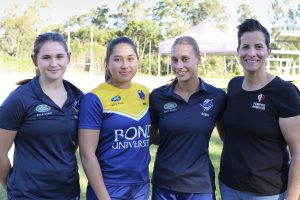 Three female rugby players in team uniforms and founder of Fempro Armour smiling for a group photo on the field