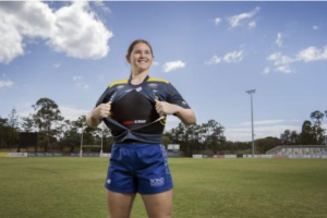 A smiling female rugby player show casing Fempro Armour rugby prototype protection gear.
