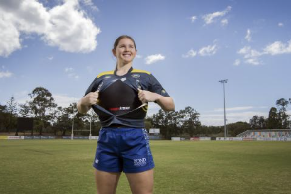 a smiling female rugby player show casing fempro armour rugby prototype protection gear