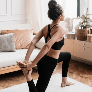 Woman practicing yoga with a dancer's pose variation in a cozy home environment