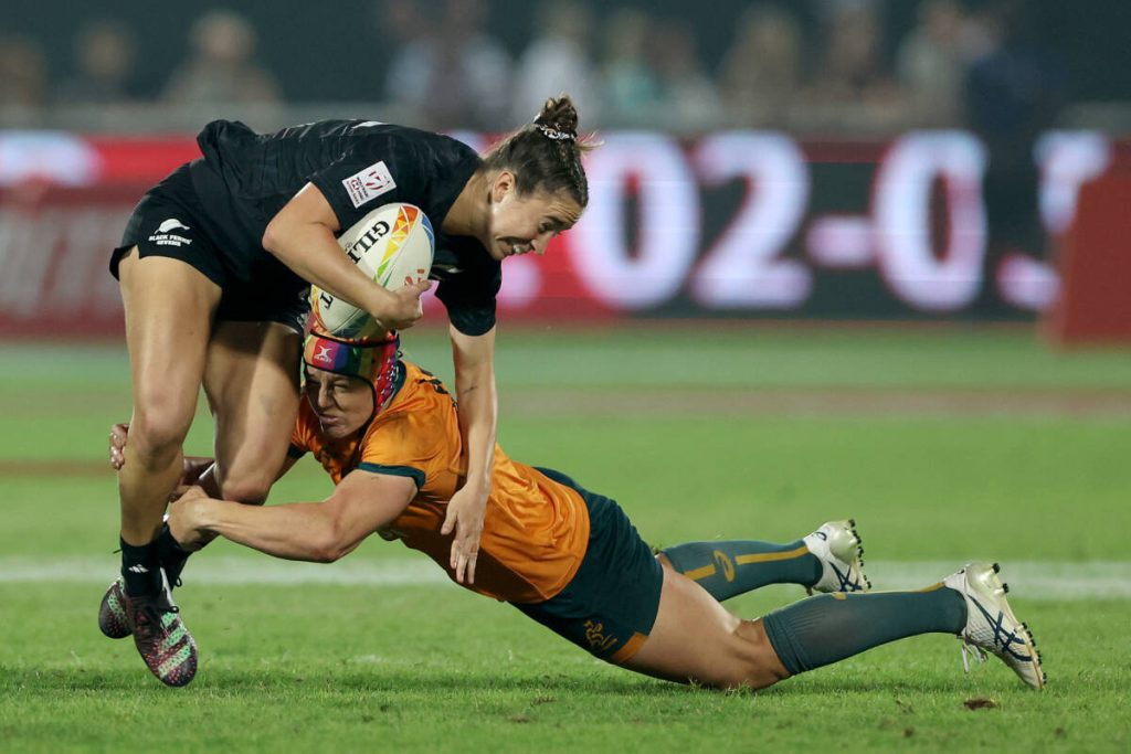 an intense moment in a womens rugby match with one player tackling another to the ground