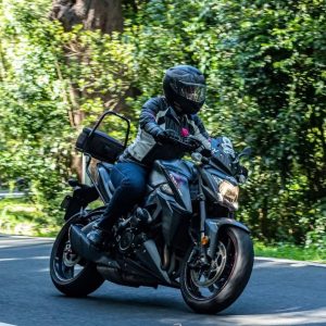 Rider on a sport touring motorcycle taking a bend on a lush forest road