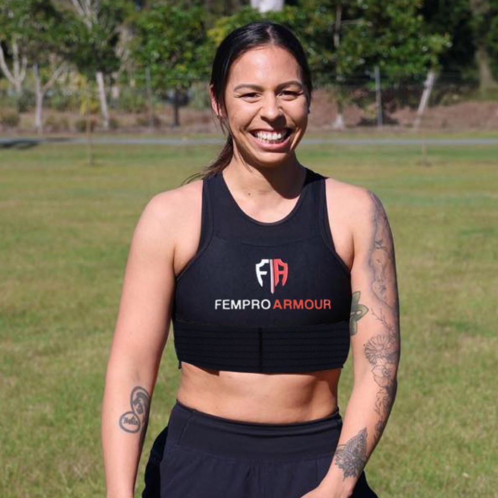 Smiling female athlete wearing Fempro Armour gear on a grassy field.