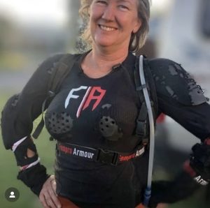Smiling woman wearing damaged Fempro Armour body armor with visible chafe marks and torn jersey after a motorcycle accident.