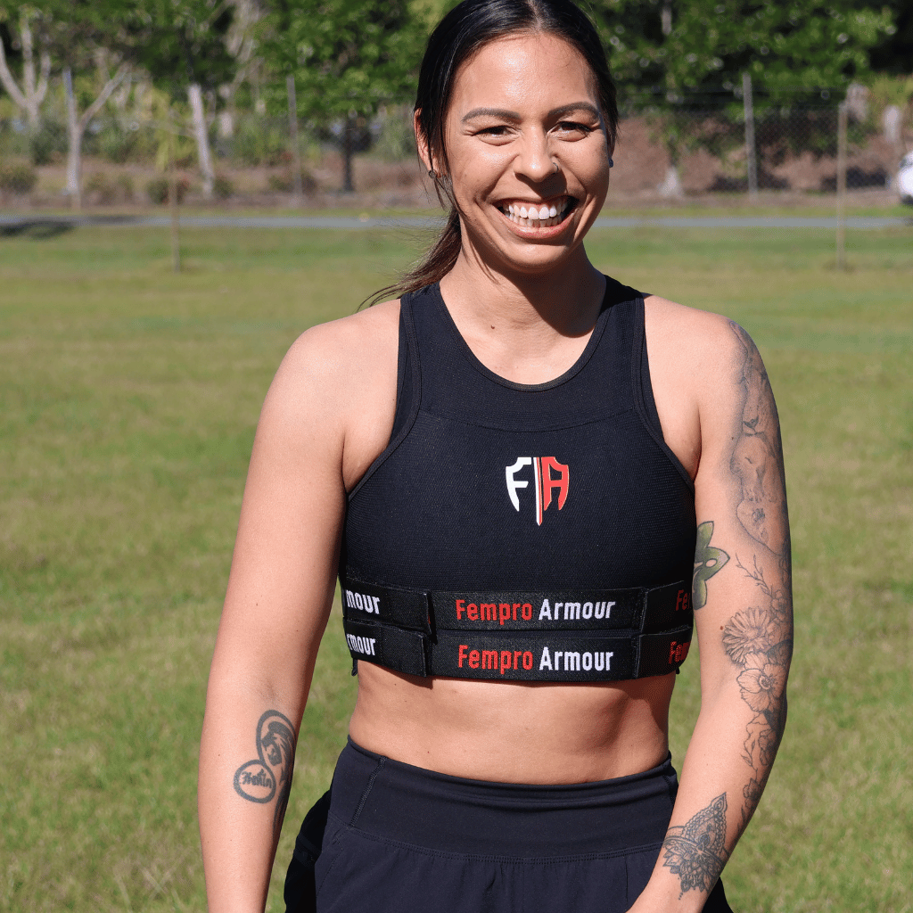 Smiling female athlete wearing Fempro Armour gear on a grassy field.