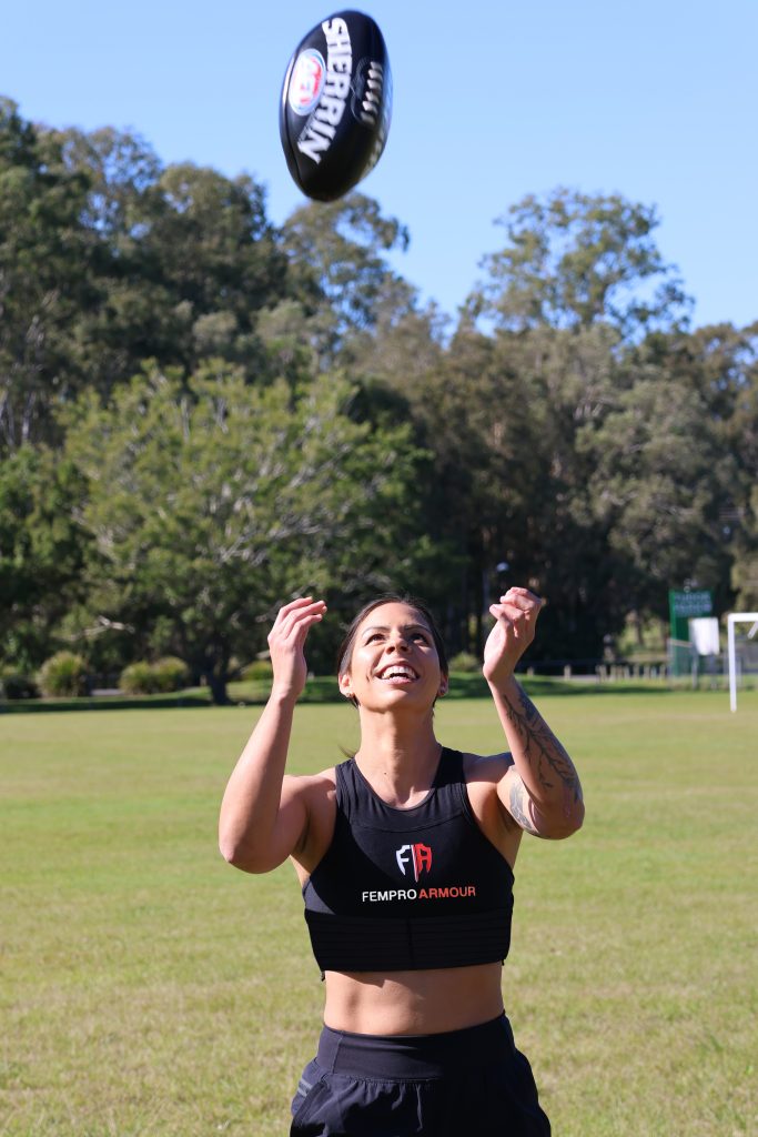 Female athlete wearing Fempro Armour gear on a grassy field.